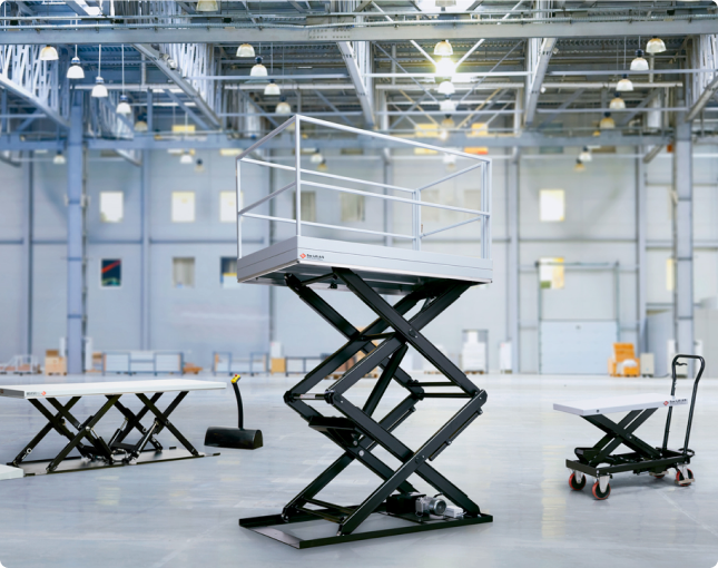 Scissor lift table with safety railing in an industrial hall